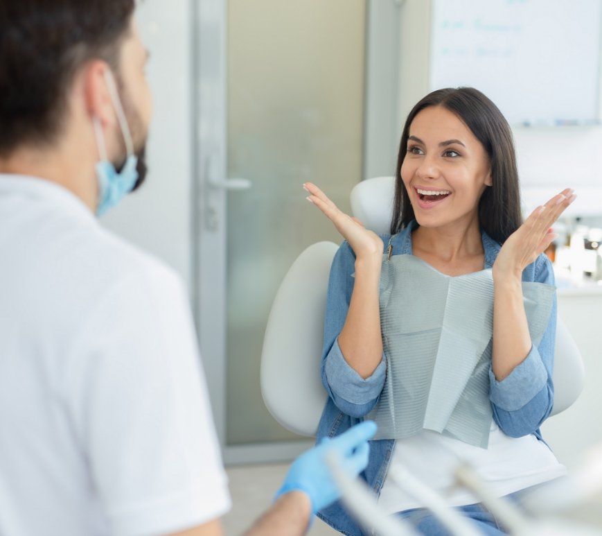 Woman in dental chair grinning at her dentist