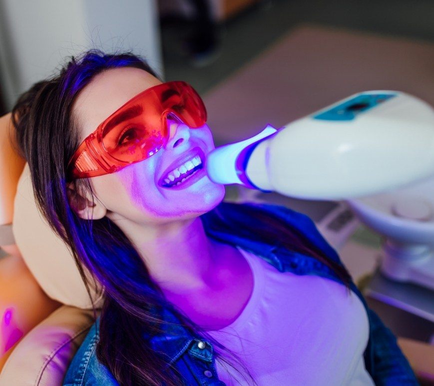 Woman getting professional teeth whitening in dental office