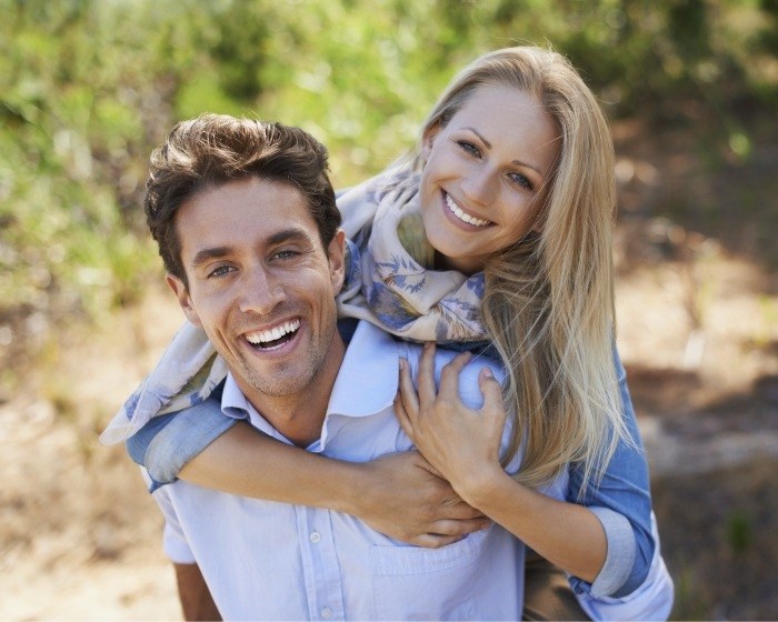 Man and woman smiling and hugging outdoors
