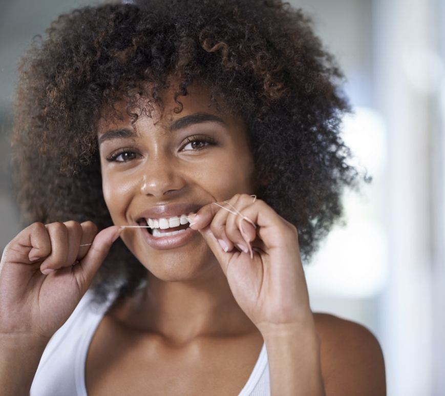 Woman smiling while flossing her teeth