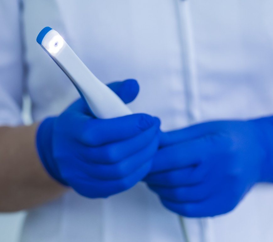 Dental professional holding a thin white intraoral camera