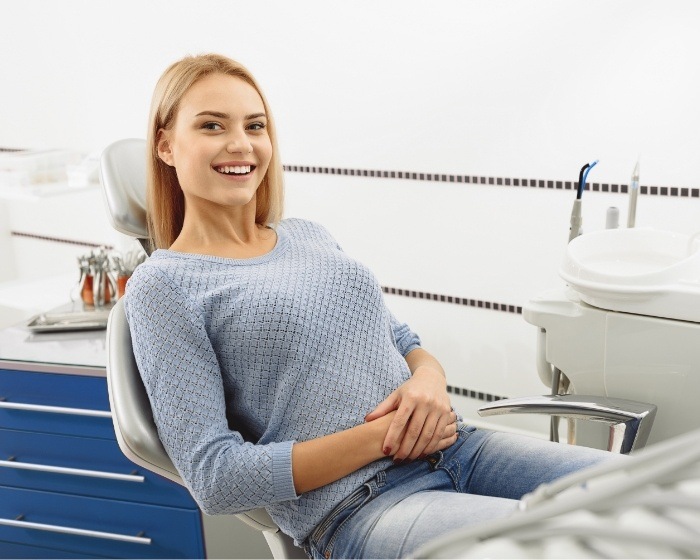 Woman in blue sweater smiling in dental chair