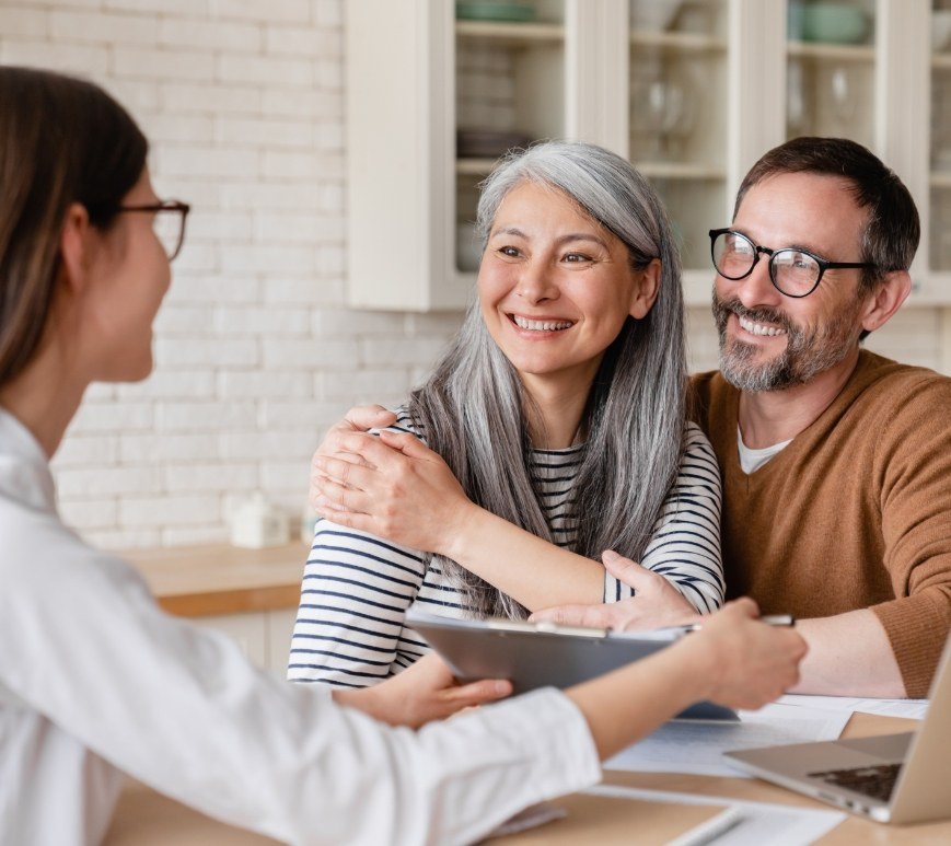 Dental team member talking to older couple at desk