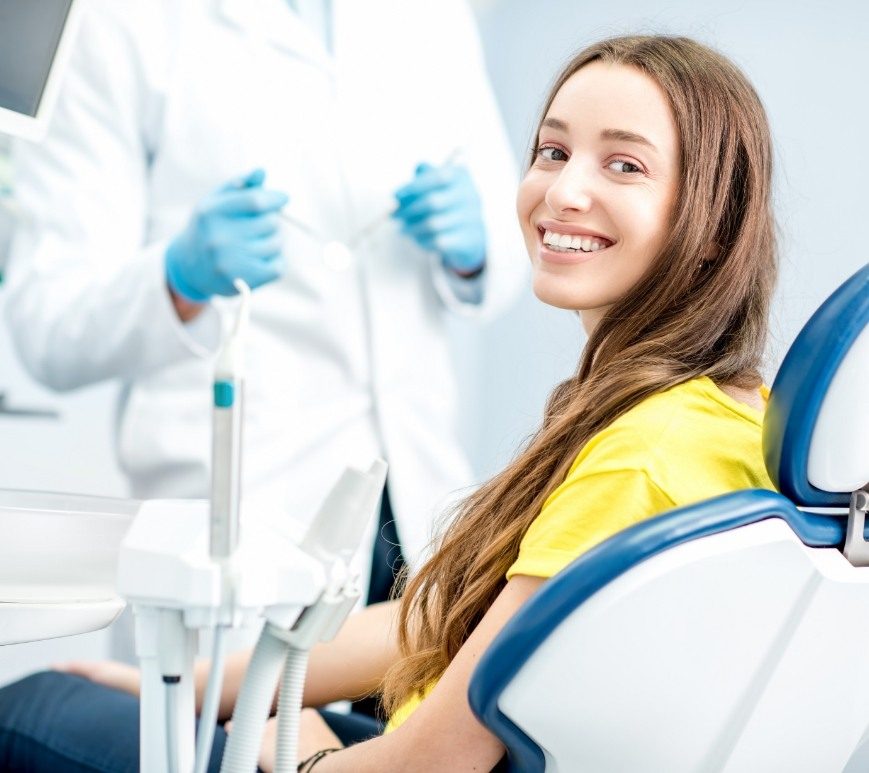 Woman in yellow blouse smiling at dental checkup