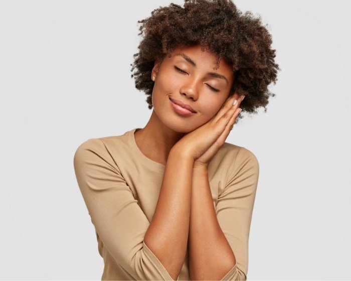 Woman making pillow shape with her hands and pretending to sleep