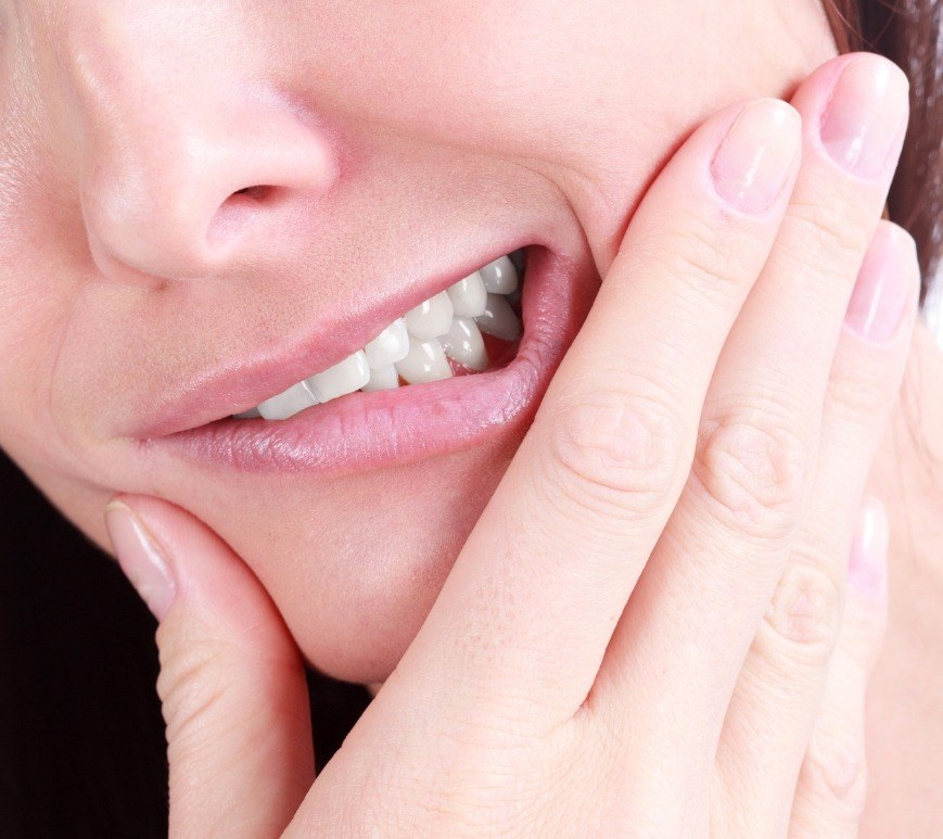 Close up of person holding their cheek and wincing in pain